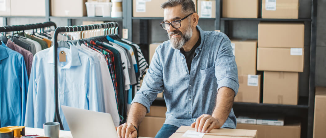 Man using a laptop in a room with lots of shipping boxes