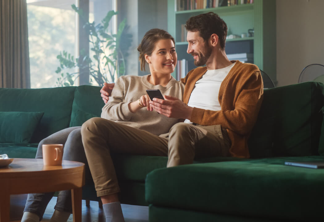 Couple sitting on a couch and looking at a smartphone