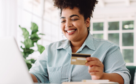 Woman holding a credit card and looking at a laptop