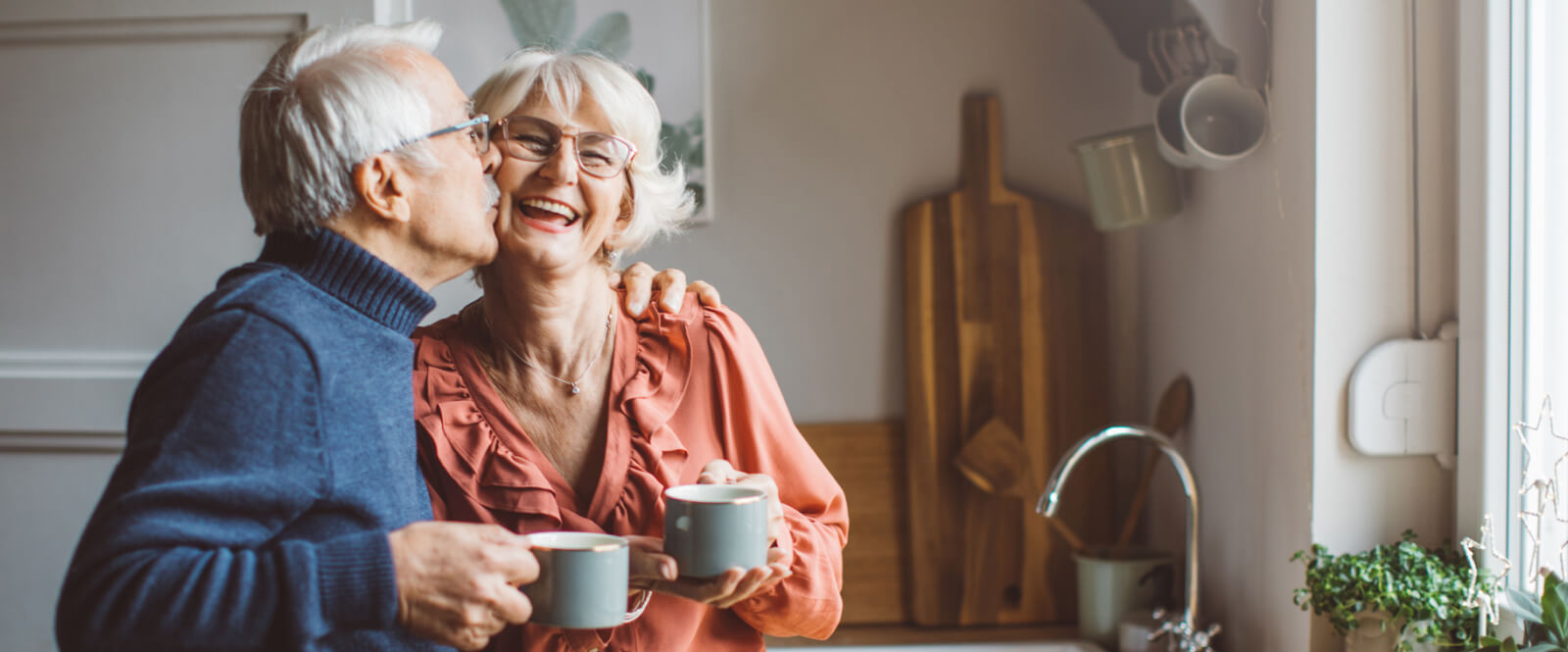 Mature couple holding coffee mugs in a kitchen